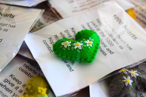 A green felt heart embroidered with white flowers 