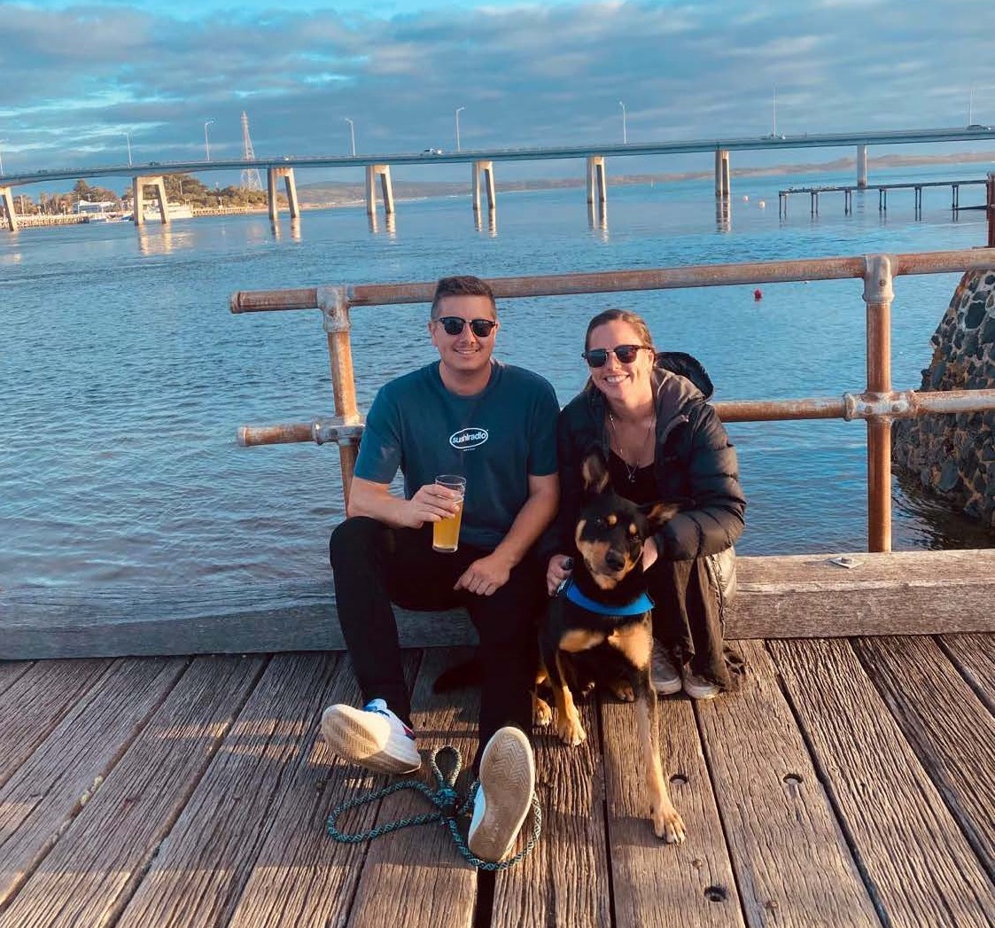 Anna and her husband Peter sit on a pier with their dog