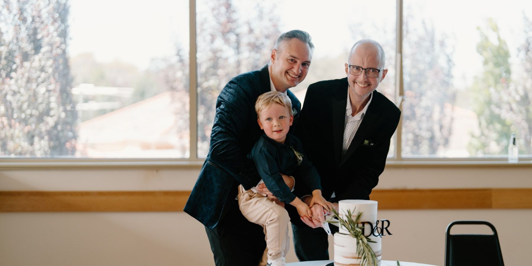 Picture of Dale and Rhys cutting the wedding cake with their son