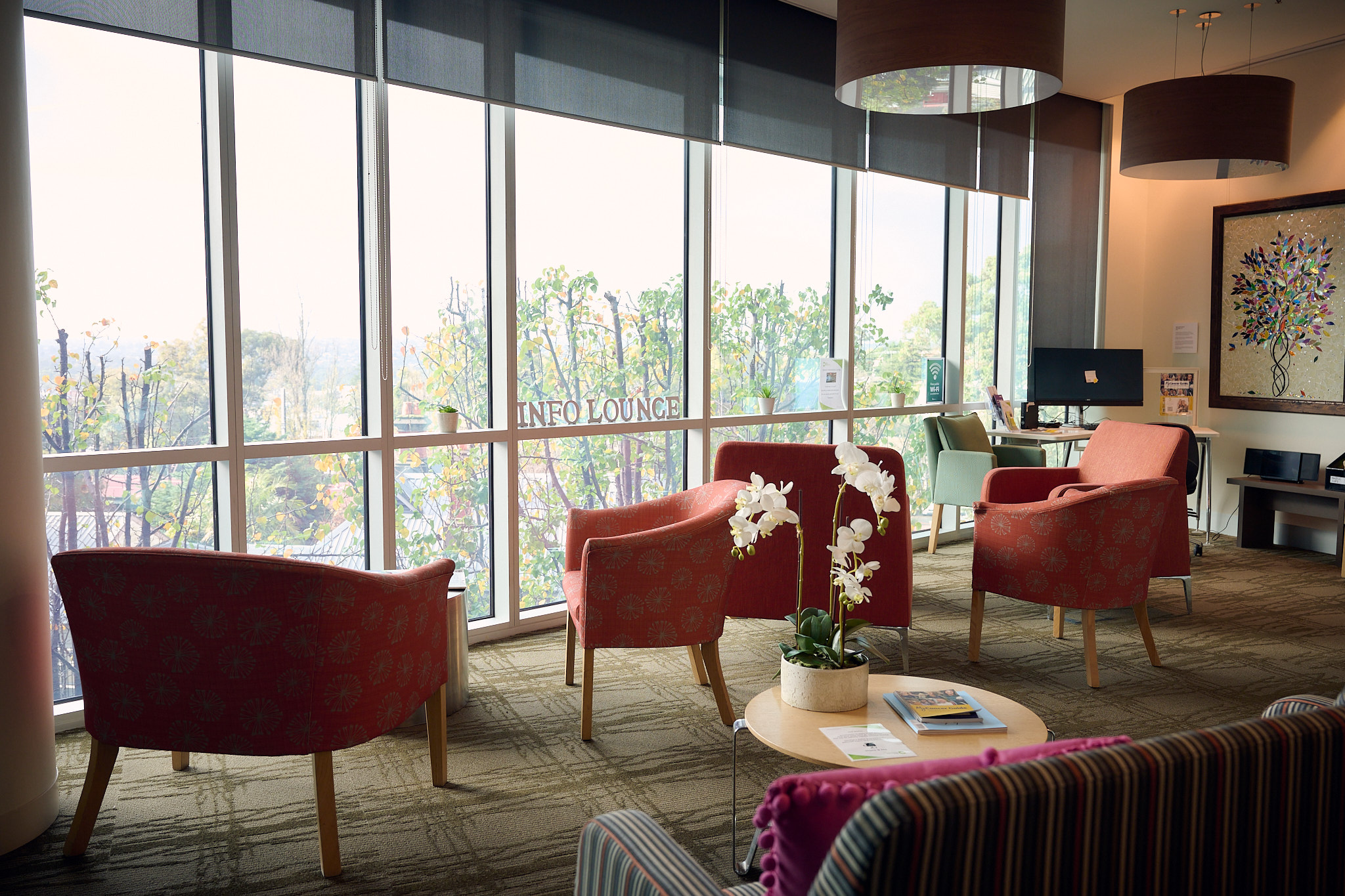Info lounge showing comfortable seating, a large window and a desk in the background