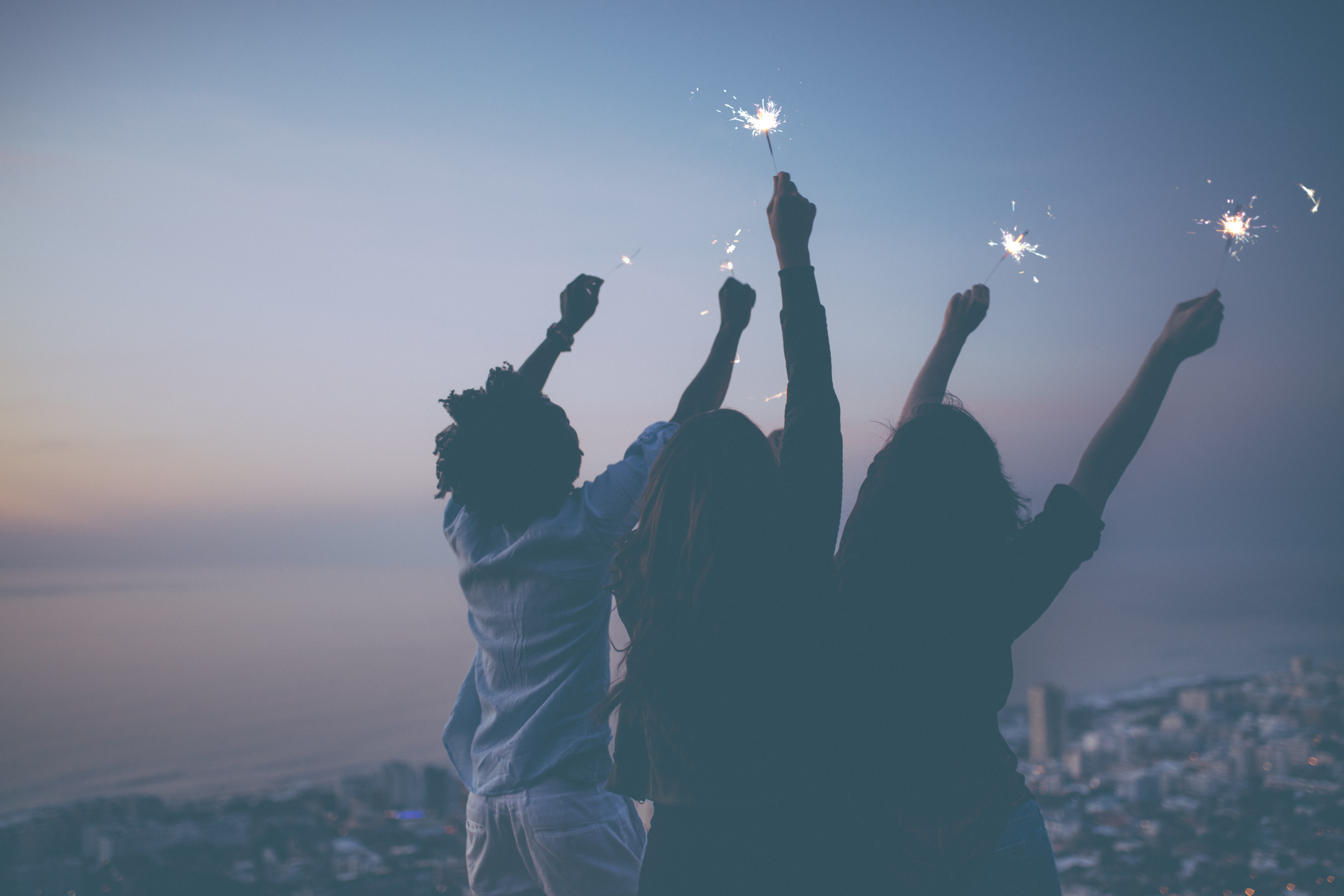 Friends-celebrating-with-sparklers-at-sunset-621830738_8574x5715